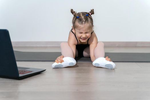 remote training of a child ballerina online during quarantine. girl doing stretching, training foot eversion.