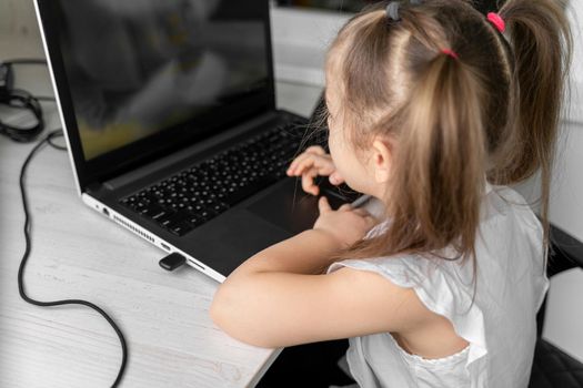 cute little caucasian girl studying online at home