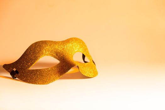 golden mask with glitter, symbol of carnival, on light background