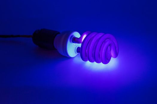 compact UV - ultraviolet CCFL - Cold Cathode Fluorescent Lamp on white surface, turned on