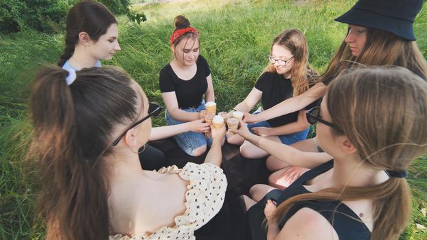 Girls friends join hands with ice cream in waffle cups in a circle