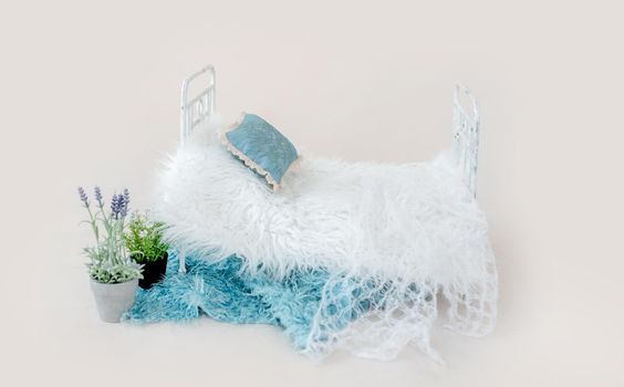 Newborn baby studio furniture tiny bed with fur decorated with flower plant. Beautiful spot for infant child studio photoshoot
