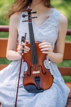 A young girl holds a violin in her hand and touches the strings