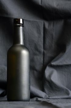 One glass black bottle against nice dark textile background