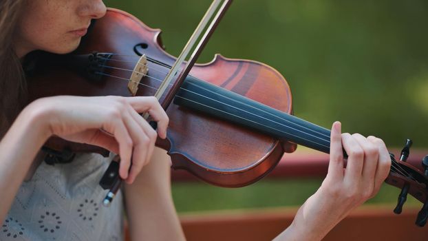 A young girl plays the violin in the city park
