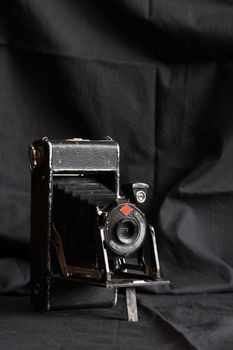 Very old photo camera against nice dark cloth background