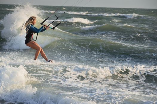 Professional kitesurfer caucasian woman rides big waves in windy weather. Kitesurfing.