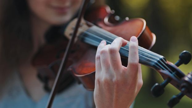 A young girl plays the violin in the city park