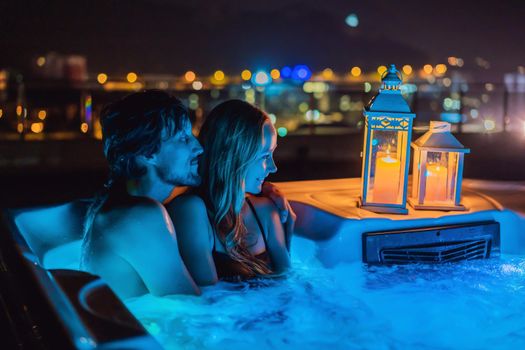 Portrait of young carefree happy smiling couple relaxing at hot tub during enjoying happy traveling moment vacation. Life against the background of green big mountains at night.