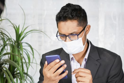 young man with face mask using smart phone indoor .