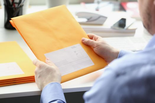 Close-up of man hold envelope, prepare package to give to courier for further delivery. Write address space on package. Delivery service, transfer concept