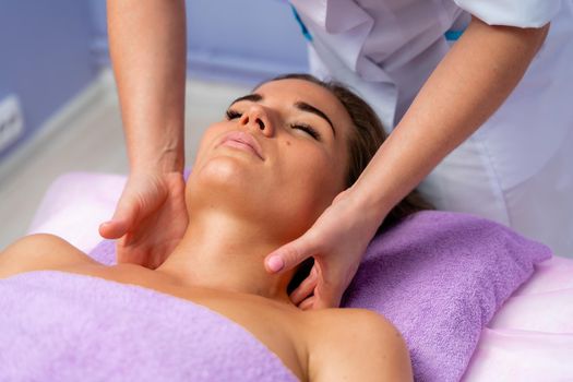 Relaxing massage. European woman getting facial massage in spa salon, side view.