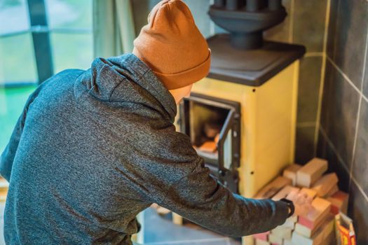 Man making fire in the fireplace. Rest in the mountains in Glamping. Cozy fireplace in a mountain house.