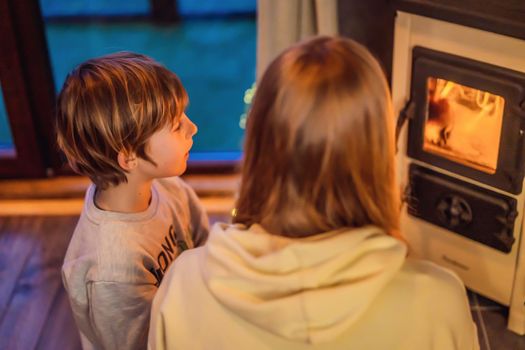 Mom and son spend time by the fireplace in Glamping. Rest in the mountains in Glamping. Cozy fireplace in a mountain house.