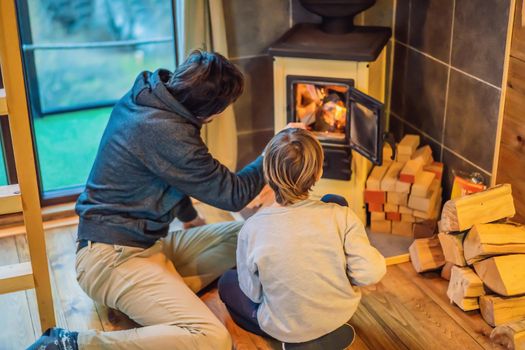 Dad and son spend time by the fireplace in Glamping. Rest in the mountains in Glamping. Cozy fireplace in a mountain house.