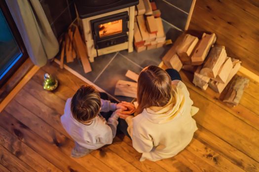 Mom and son spend time by the fireplace in Glamping. Rest in the mountains in Glamping. Cozy fireplace in a mountain house.