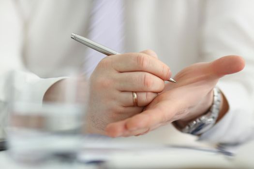 Close-up of male writing note with silver pen on his hand to keep in mind some information. Try not to forget, to do list, reminder. Note, memory concept