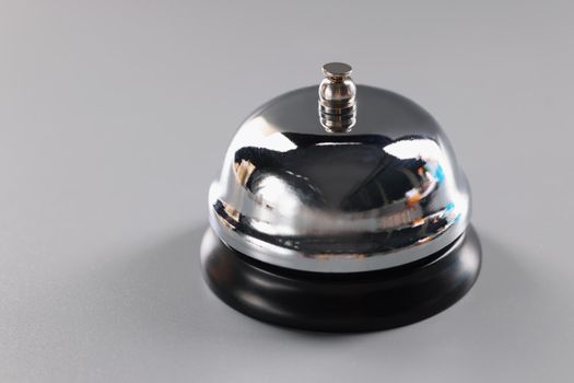 Close-up of silver bell stands on grey surface to attract attention, press bell to call service. Thing to put on reception. High quality service concept