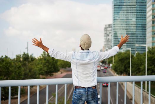 Portrait from behind of young male with arms raised outside