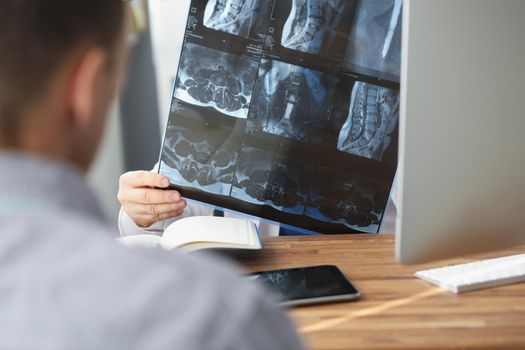 Close-up of doctor examining patients xray result in hospital on appointment with client. Scan of persons back. Healthcare, medicine, diagnostic concept