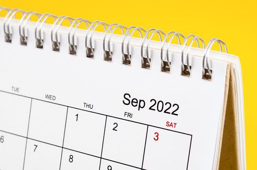 Close-up September 2022 desk calendar on yellow background.
