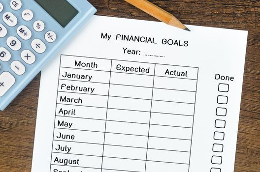 My planning financial goals form and wooden pencil with calculator on wooden background.