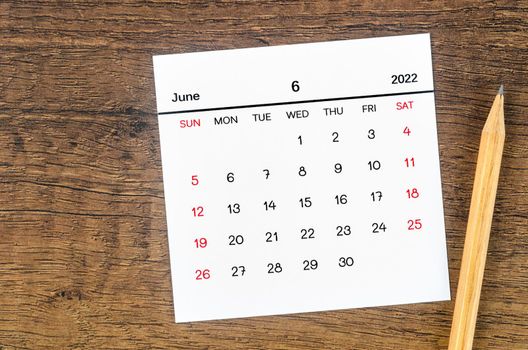The June 2022 calendar and wooden pencil on vintage wooden background.