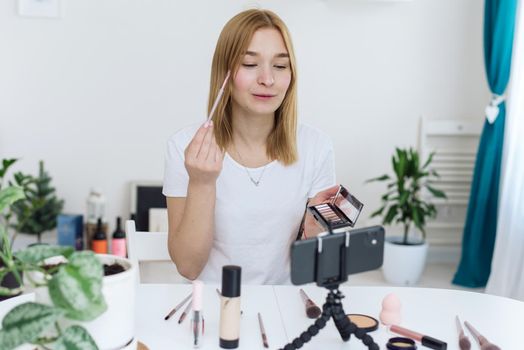 Vlogger testing decorative cosmetic and broadcast live video to social network at home. Blogging, videoblog, makeup concept.