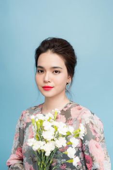 Portrait of tender asia woman with bouquet  on blue background