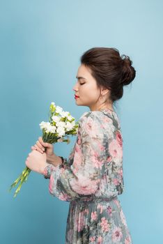 Charming asia girl in flower dress standing on blue background