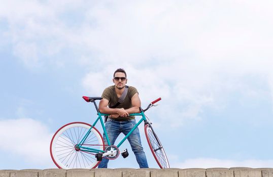 young hipster man riding fixed gear bike on city street