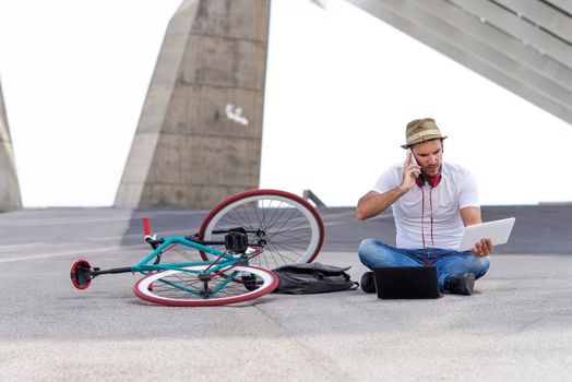 Young male wearing sunglasses relaxing on the floor and listening music.