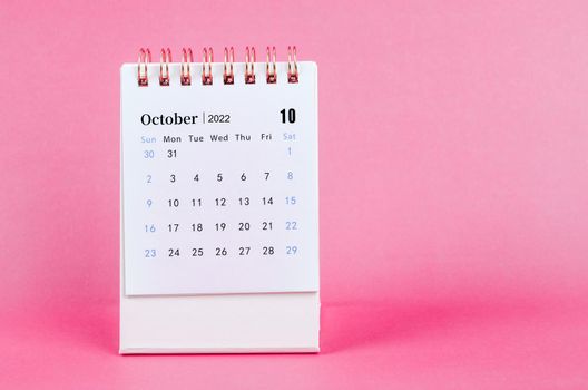 The October 2022 desk calendar on pink background.