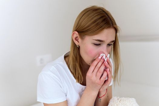 Sick millennial woman feeling bad, weak fight against flu, runny nose, rest at home, health problem concept. The woman blows her nose into a handkerchief. depression, sadness and crying.