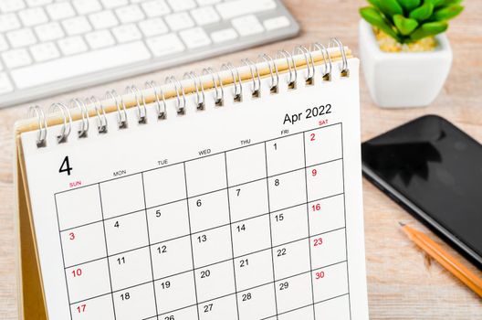 The April 2022 desk calendar on wooden table.