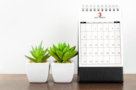 March 2022 desk calendar on wooden table.