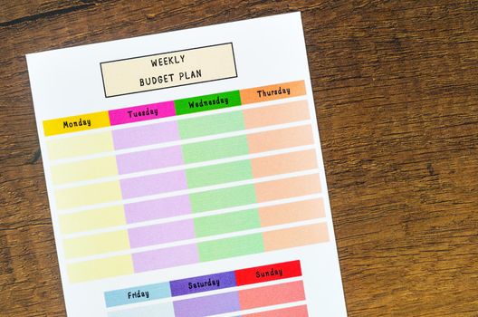 Weekly budget plan form on wooden background.