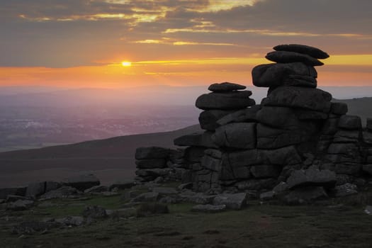 Beautiful sunset with orange sky and clouds over Great Staple Tor and the valley below, Dartmoor National Park, Devon, UK