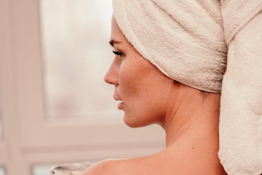 Young serene relaxed woman in spa bath towel drinking hot beverage tea coffee after taking shower bath at home. Beauty treatment, hydration concept