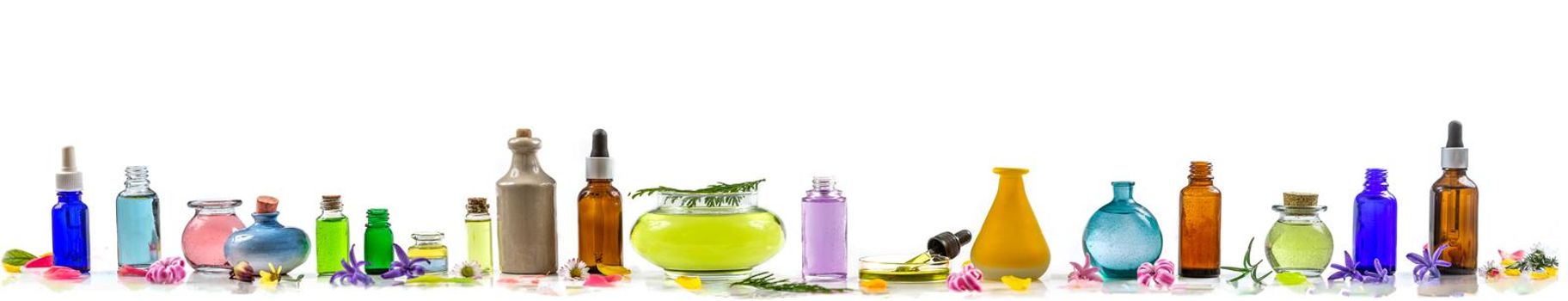 Panel of essential oils in various bottles aligned on a panoramic white background