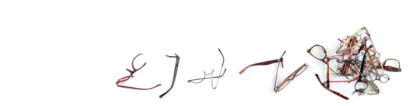 Old pairs of glasses lined up in panoramic view on a white background.