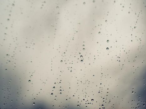 Raindrops on the surface of window glass with a blurred background.