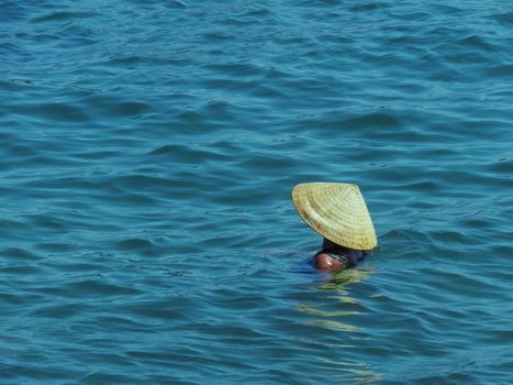 woman in vietnamese hat swims in the sea