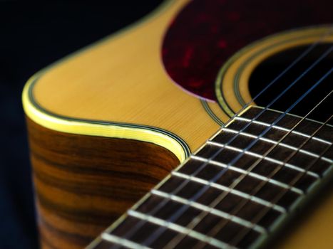 six - string acoustic guitar  on a black background. low key. music day