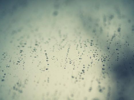 Raindrops on the surface of window glass with a blurred background.