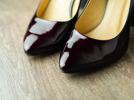 dark burgundy lacquered loafers on a wooden background close-up