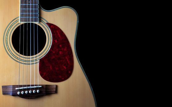 six - string acoustic guitar  on a black background. low key. music day