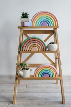 On a wooden shelf there are cubes and a rainbow. Children's room decor. Environmentally friendly toys for children. Wooden rainbows made of natural material. Zero waste toys.