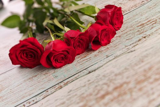 Low Angle View of Red Roses on Rustic Wood Table. There are 5 roses in total. High quality photo