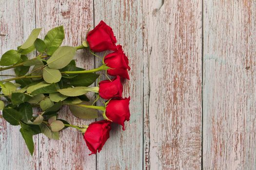 Directly Above Overhead Flatlay View of Red Roses on a weathered Rustic Wood Table. There are 5 roses in total. High quality photo
